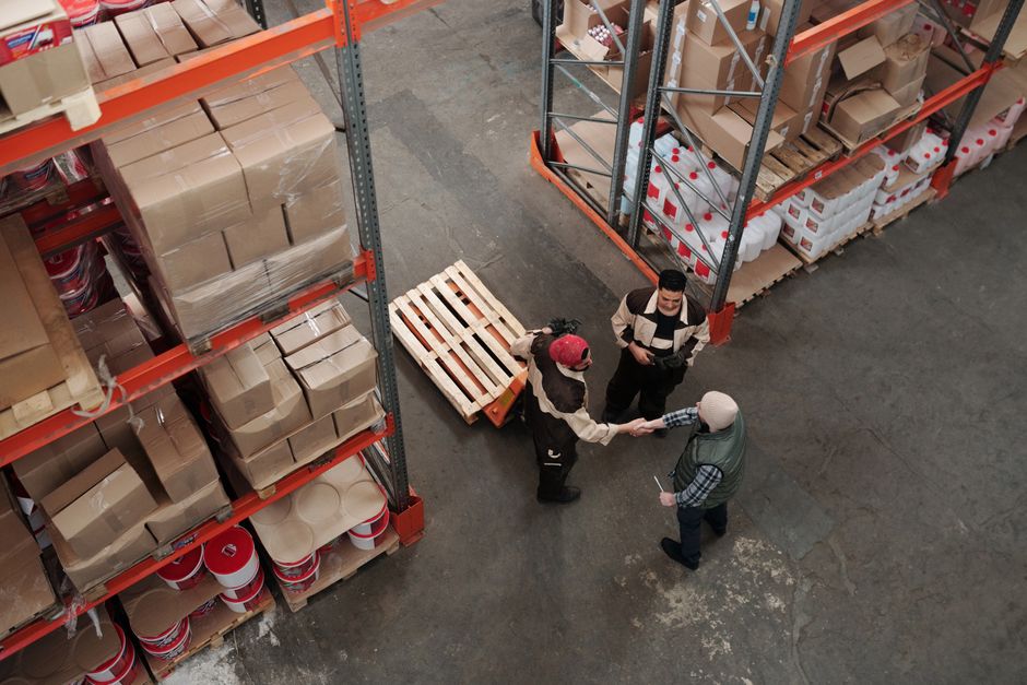 High angle view of workers shaking hands in a warehouse, symbolizing teamwork and logistics.